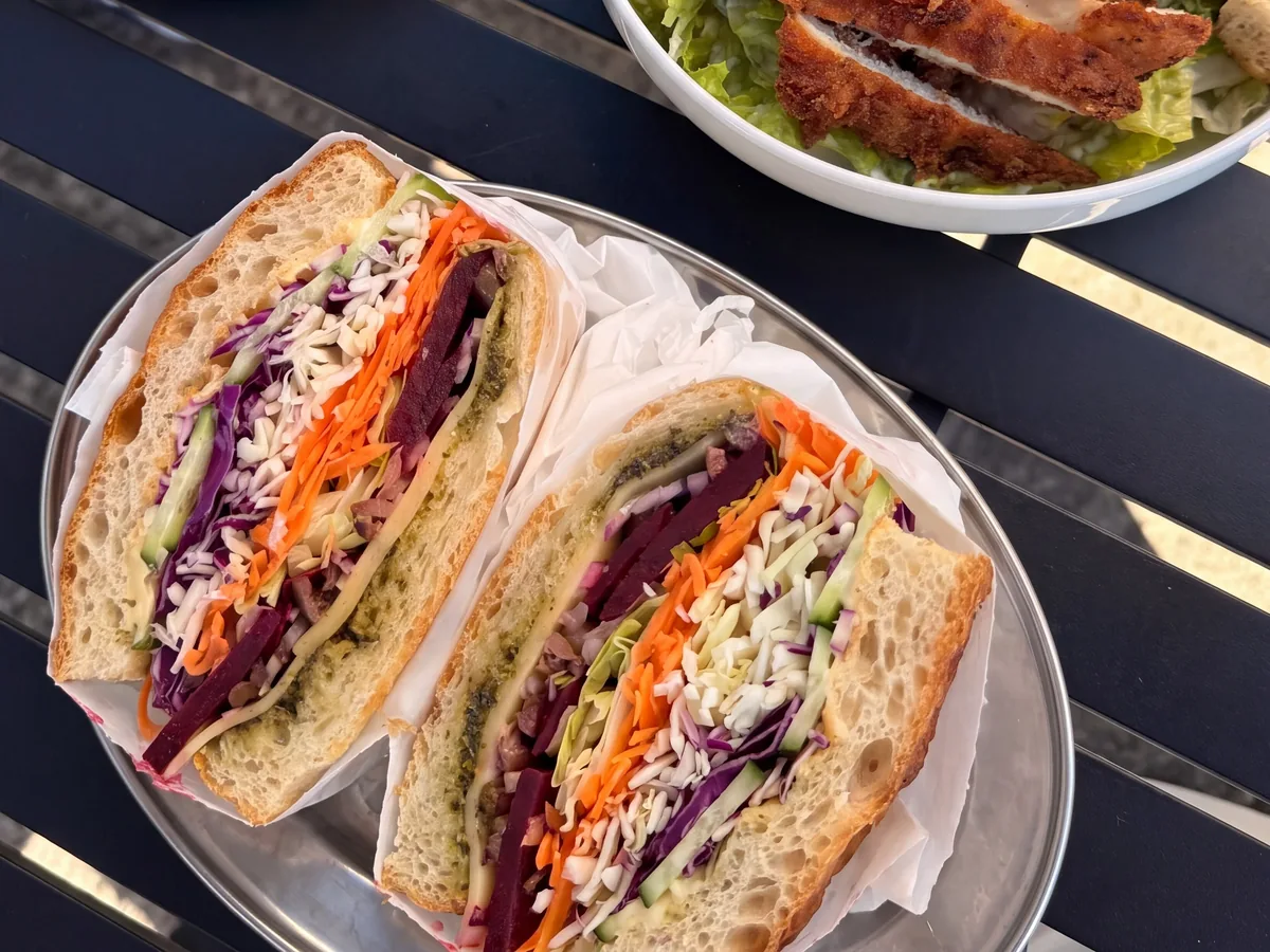 Two salad focaccias cut open on a steel tray, from above on a black table