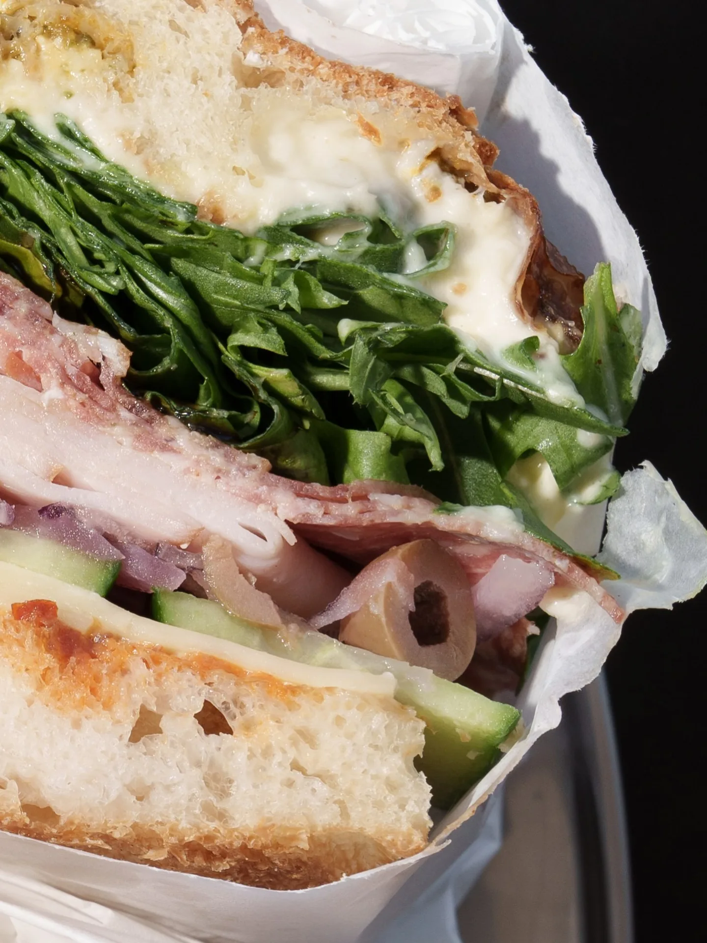 The Deli focaccia cut open: rocket, stracciatella, ham, salami and olives