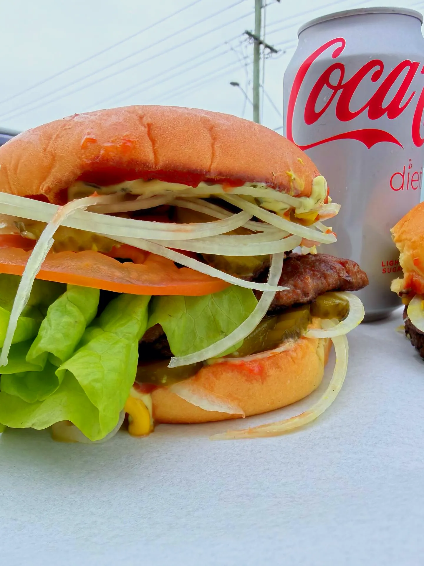 A smash burger with lettuce and tomato on a white bench